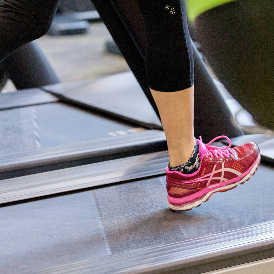 A female health club member running on a treadmill at Woodbury Park's gym